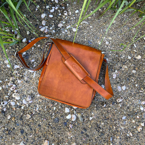 The Floto Siena leather shoulder sling bag is a men's messenger bag that is handcrafted in Italy. This is the Siena Field Bag in Olive Honey Brown - beach 2